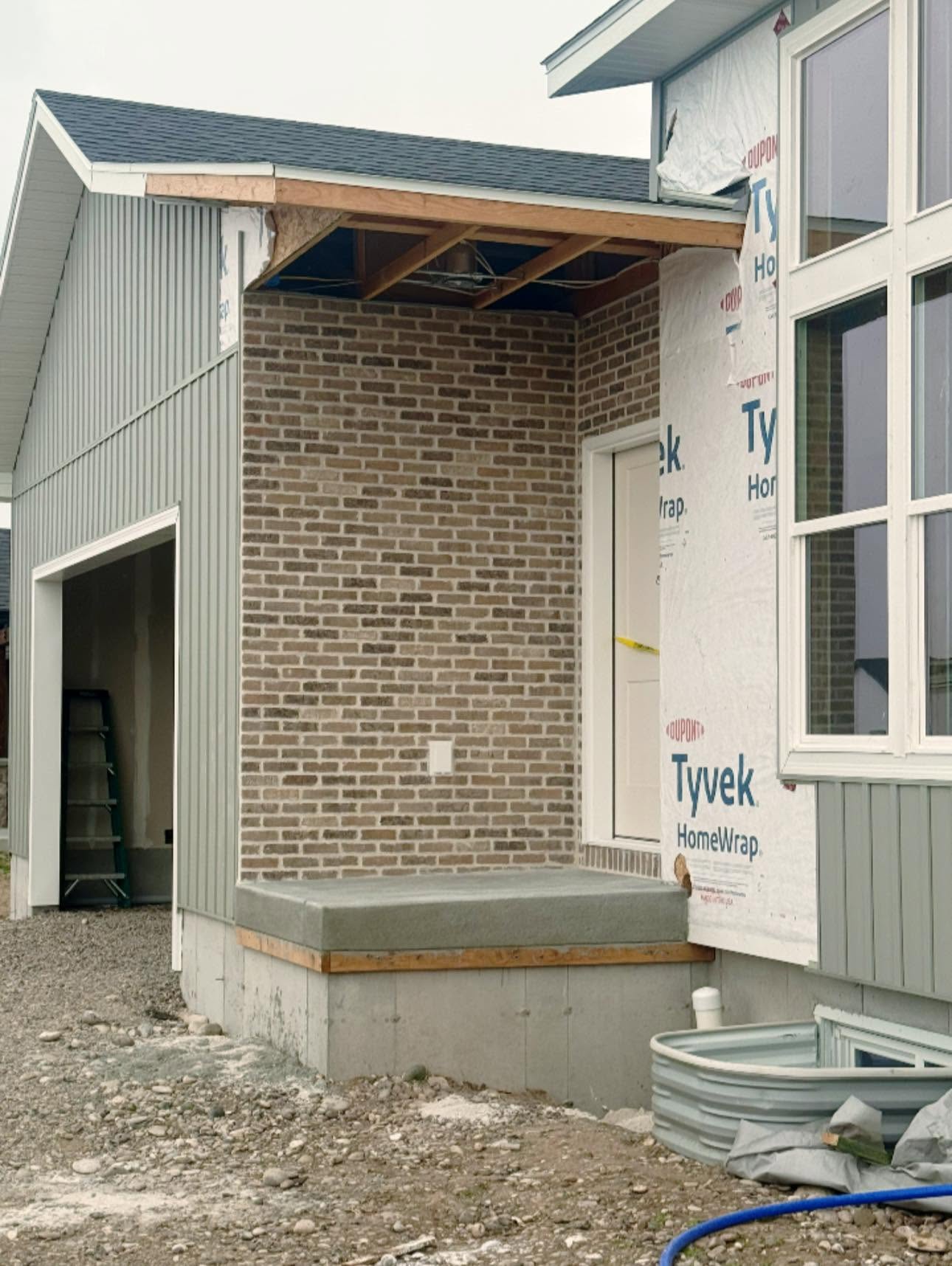Brick entry surround beside unfinished house wrap